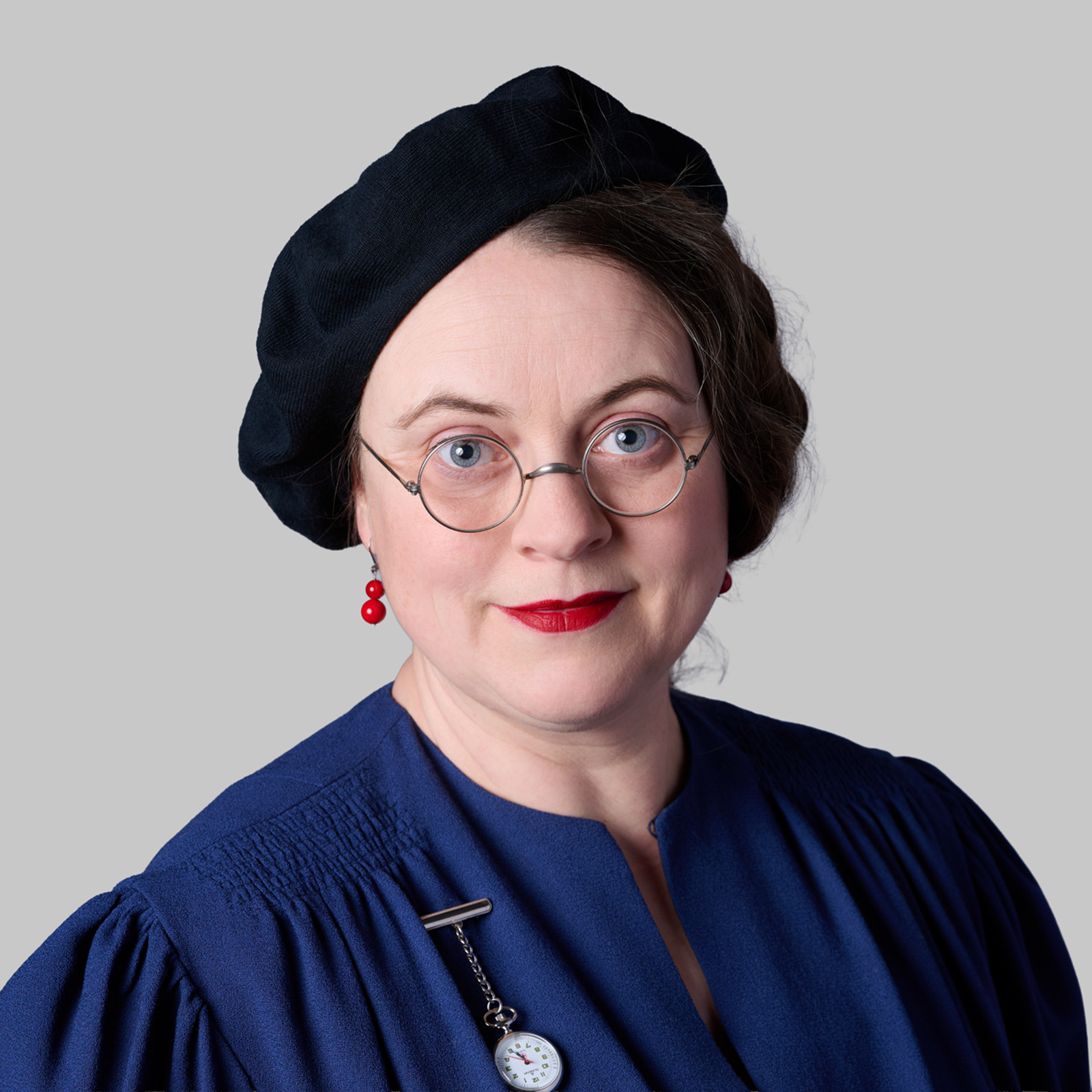 Professional corporate portrait of a woman with glasses against a grey background